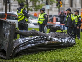 A statue of Sir John A. Macdonald lies at the base of the monument in Place du Canada from which it was pulled during a demonstration by the Coalition for BIPOC Liberation in Montreal on Saturday, Aug. 29, 2020.