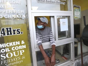 Ivoran Anson looks up at a bullet hole from the takeout window at a Spence's Bakery West Indian restaurant on Tuesday where six people were wounded hours earlier.