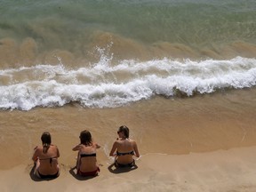 Women sit on the sand.