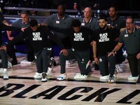 Toronto Raptors players and coaches kneel during the playing of the anthems before a Sept. 1 game against the Boston Celtics.