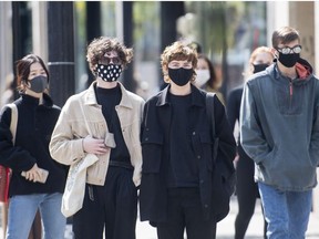 People wear face masks as they wait to cross a street in Montreal, Monday, September 21, 2020, as the COVID-19 pandemic continues in Canada and around the world.