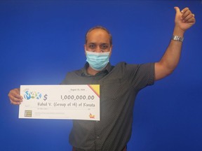 Rahul Vohra, one of a group of 14 COVID-19 researchers from Ottawa-Gatineau who won $1 million in a LOTTO Max draw, poses with the oversized cheque representing the group's prize.