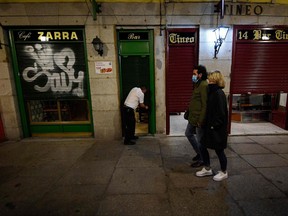 A couple walk past an closing a bar at the end of a day's work at Plaza Mayor in Madrid on October 24, 2020.