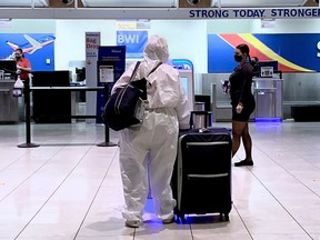 In this file photo taken on October 21, 2020 a woman in a full hazmat suit checks in for her flight at Baltimore Washington International Airport in Baltimore, Maryland.
