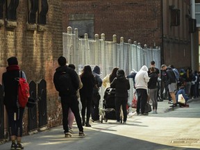 People wait in line in an alleyway at a COVID assessment centre at St. Michael's Hospital, in Toronto, Sept. 22, 2020. A new survey suggests Canadians continue to experience mental health difficulties due to the pandemic, with one in four saying their stress level is higher than during the first COVID-19 wave.