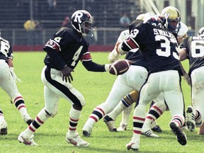 Chris Issac prepares to hand off to Rough Riders teammate Skip Walker during a 1983 CFL game against the Winnipeg Blue Bombers.