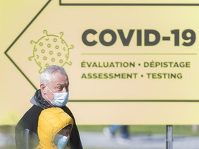 People wear face masks outside a COVID-19 testing clinic Montreal, Sunday, October 11, 2020.