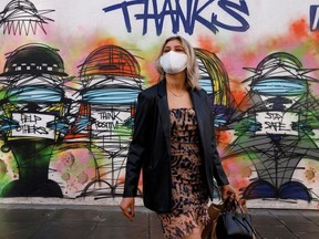 A woman wearing a face mask stands in front of graffiti, amid the coronavirus disease (COVID-19) outbreak, in central London Britain October 15, 2020.