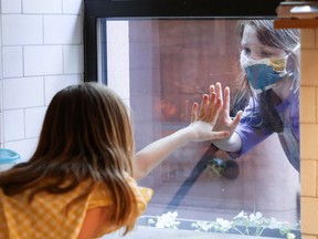 Children say hi through a kitchen window.