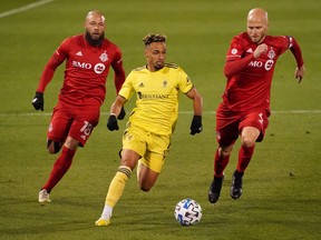 Nashville SC midfielder Hany Mukhtar runs with the ball against Toronto FC midfielders Nick DeLeon (left) and Michael Bradley.