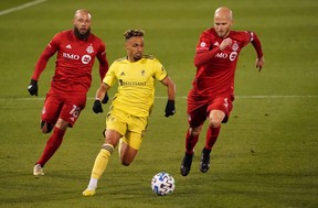 Nashville SC midfielder Hany Mukhtar runs with the ball against Toronto FC midfielders Nick DeLeon (left) and Michael Bradley.