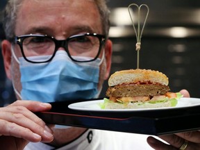 Chef Sam Brunschweiler wears a protective mask as he displays a pea protein-based hamburger with vegan juicy meat flavour, tomato, salad and sesame bun on a plate at flavour maker Givaudan's innovation centre in Kemptthal, Switzerland, Oct. 29, 2020.