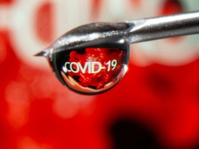 The word "COVID-19" is reflected in a drop on a syringe needle in this illustration taken November 9, 2020.