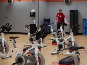 Files: A staff member wearing a protective mask cleans stationary bikes after a spin class at a GoodLife Fitness Centers Inc. gym on its first day of reopening in Ottawa, Ontario, Canada, on Friday, July 17, 2020.