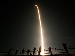 People watch as a SpaceX Falcon 9 rocket, topped with the Crew Dragon capsule, is launched carrying four astronauts on the first operational NASA commercial crew mission at Kennedy Space Center in Cape Canaveral, Florida, U.S. November 15, 2020.