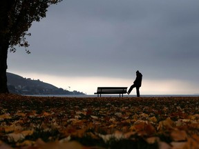 A man stretches on a bench on a misty autumn morning.