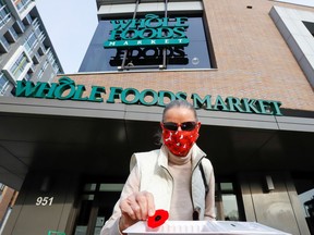 Dagmar Dohler takes a poppy that is given away in front of a Whole Foods store in Ottawa, Ontario, Canada, on Nov. 6, 2020.