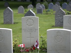 In this file photo taken on Saturday, July 26, 2014, wooden crosses and Canadian flags adorn the grave of World War I Canadian soldier Pvt. George Lawrence Price, center, at the St. Symphorien Cemetery near Mons, Belgium. Price was recorded as the last Canadian soldier to die on the Western Front during the First World War.
