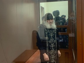 Father Sergiy Romanov, a coronavirus-denying priest suspended by the Russian Orthodox Church for disobeying orders, stands inside a defendants' cage during a court hearing in Moscow on Tuesday.