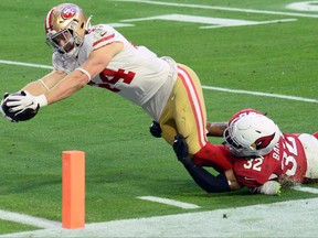 San Francisco 49ers fullback Kyle Juszczyk, left, dives for a touchdown against Arizona Cardinals strong safety Budda Baker during the second half at State Farm Stadium in Glendale, Ariz., Dec. 26, 2020.