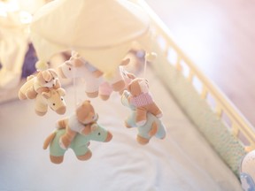 Close-up baby crib with musical animal mobile at nursery room.