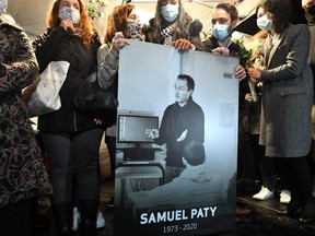 Relatives and colleagues hold a picture of Samuel Paty during the 'Marche Blanche' in Conflans-Sainte-Honorine, northwest of Paris, on Oct. 20, 2020, in solidarity after a teacher was beheaded for showing pupils cartoons of the Prophet Mohammed.