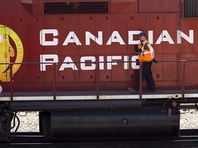 A Canadian Pacific Railway employee walks along the side of a locomotive in a marshalling yard in Calgary on May 16, 2012.