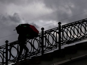 A woman shelters from the rain under an umbrella.