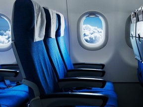 Empty air plane seats. Blue sky and clouds in the window. Airplane interior