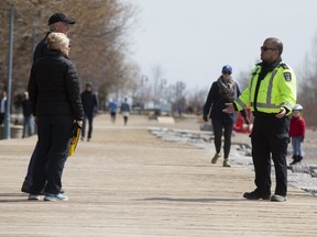 A city bylaw enforcement officer addresses a couple in the eastern beaches on April 11, 2020.