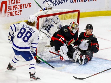 Senators centre Josh Norris slides into goaltender Matt Murray as Maple Leafs right-winger Wayne Simmonds, top, and William Nylander surround the net.