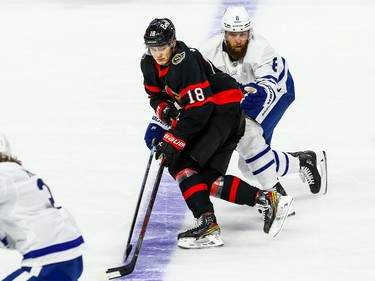 Senators left-winger Tim Stuetzle tries to get past Maple Leafs defenceman Jake Muzzin to get into position to accept a pass from a teammate.