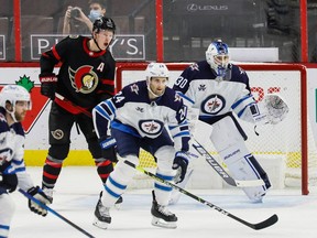 Senators left-winger Brady Tkachuk and Jets defenceman Derek Forbort watch for a shot heading toward the net of goaltender Laurent Brossoit (30) during the second period of Winnipeg's 4-3 overtime win on Tuesday, Jan. 19, 2021.