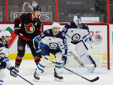 Senators left-winger Brady Tkachuk and Jets defenceman Derek Forbort watch for a shot heading toward the net of goaltender Laurent Brossoit (30) during the second period.