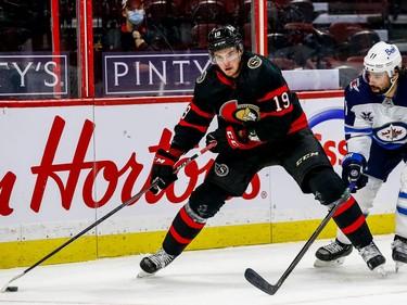 Senators right-winger Drake Batherson protects the puck from defensive pressure by the Jets' Nate Thompson the third period of play.