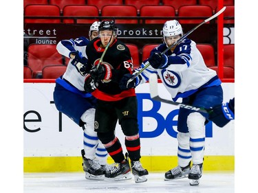 Senators right-winger Evgenii Dadonov squeezes through the check of Jets defenceman Logan Stanley and left-winger Adam Lowry, right, in the first period.