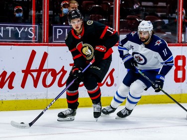 Senators right-winger Drake Batherson keeps the puck away from Jets centre Nate Thompson during first-period action.
