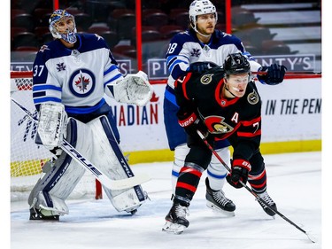 Senators left-winger Brady Tkachuk battles with Jets defenceman Nathan Beaulieu in front of goaltender Connor Hellebuyck in the first period.