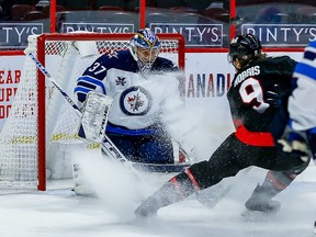 Jets goaltender Connor Hellebuyck makes a save against Senators centre Josh Norris during the first period of Thursday's game at Canadian Tire Centre.