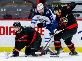 Senators left-winger Brady Tkachuk and right-winger Drake Batherson get the puck away from Jets left-winger Adam Lowry in the first period at the Canadian Tire Centre on Thursday.