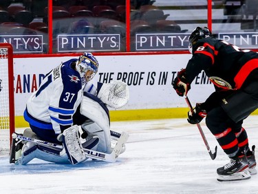 Jets goaltender Connor Hellebuyck makes a save against Senators right-winger Connor Brown on a third-period breakaway.