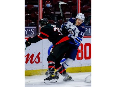 Senators centre Colin White checks the Jets' Mark Scheifele during third-period play.