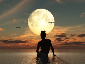 Woman in the sea watching the full moon