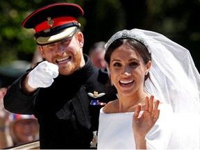 Britain's Prince Harry gestures next to his wife Meghan as they ride a horse-drawn carriage after their wedding ceremony at St George's Chapel in Windsor Castle in Windsor, Britain, May 19, 2018.