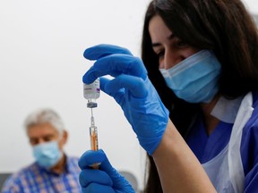 A health worker fills a syringe with a dose of the COVID-19 vaccine.