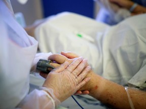 FILE: A staff member wearing gloves works holds the hand of a patient.