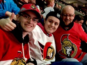 Brian Fraser, left, who turned his fight with leukemia into a much-publicized awareness campaign, died Thursday at age 26. He is pictured here at an Ottawa Senators game with his brother, Tait, and father Rick.