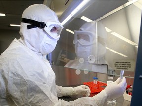 Manufacturing Associate Leon Barbeau looks at a sample under the clean hood in the Bio Therapeutics lab's virus manufacturing centre at the The Ottawa Hospital.