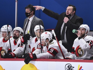 Senators head coach D. J. Smith pulls down his mask to call out instructions during the third period of Thursday's game against the Canadiens.