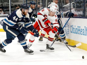 Ryan Dzingel (right) of the Carolina Hurricanes and Vladislav Gavrikov (left) of the Columbus Blue Jackets battle for control of the puck during the third period at Nationwide Arena on February 7, 2021 in Columbus, Ohio. Carolina defeated Columbus 6-5.